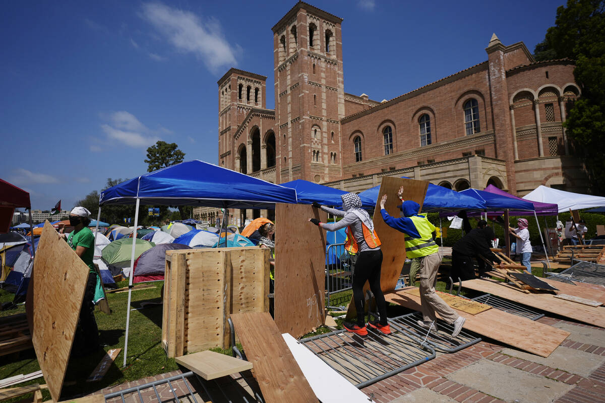 Demonstrators restore a protective barrier at an encampment on the UCLA campus, the morning aft ...