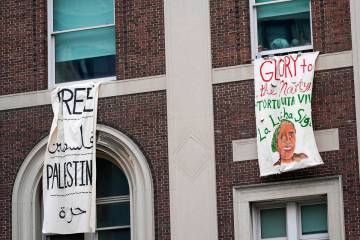 A demonstrator pumps his fist as he hangs a sign from a window in Hamilton Hall inside the Colu ...