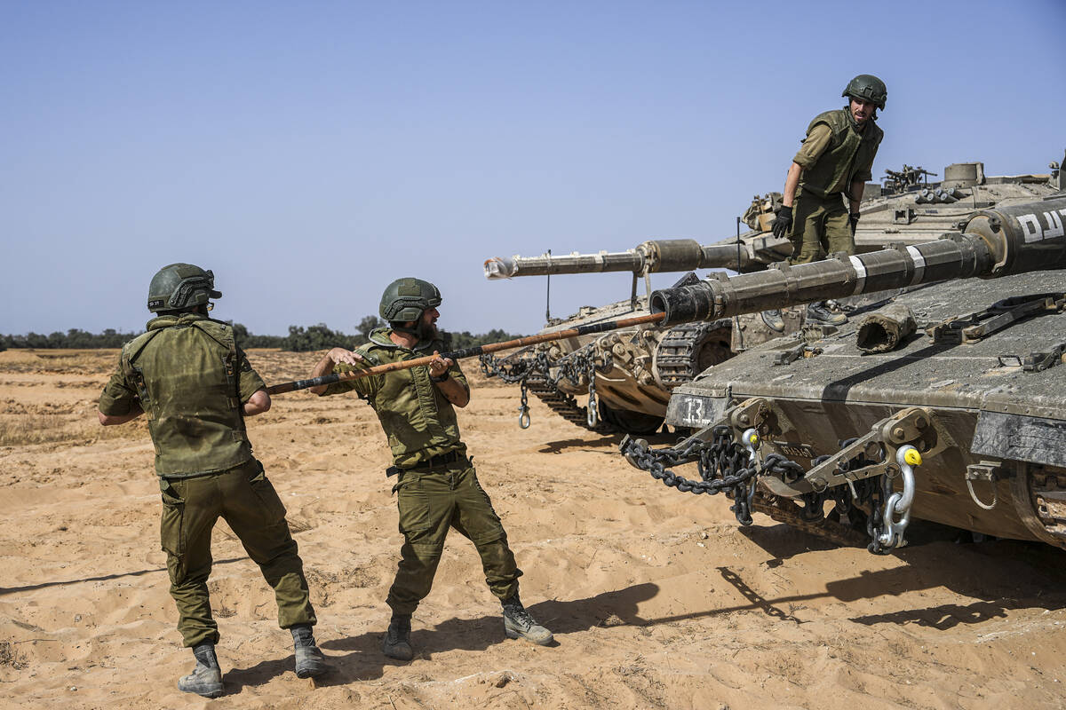Israeli soldiers work on a tank at a staging ground near the border with the Gaza Strip, in sou ...