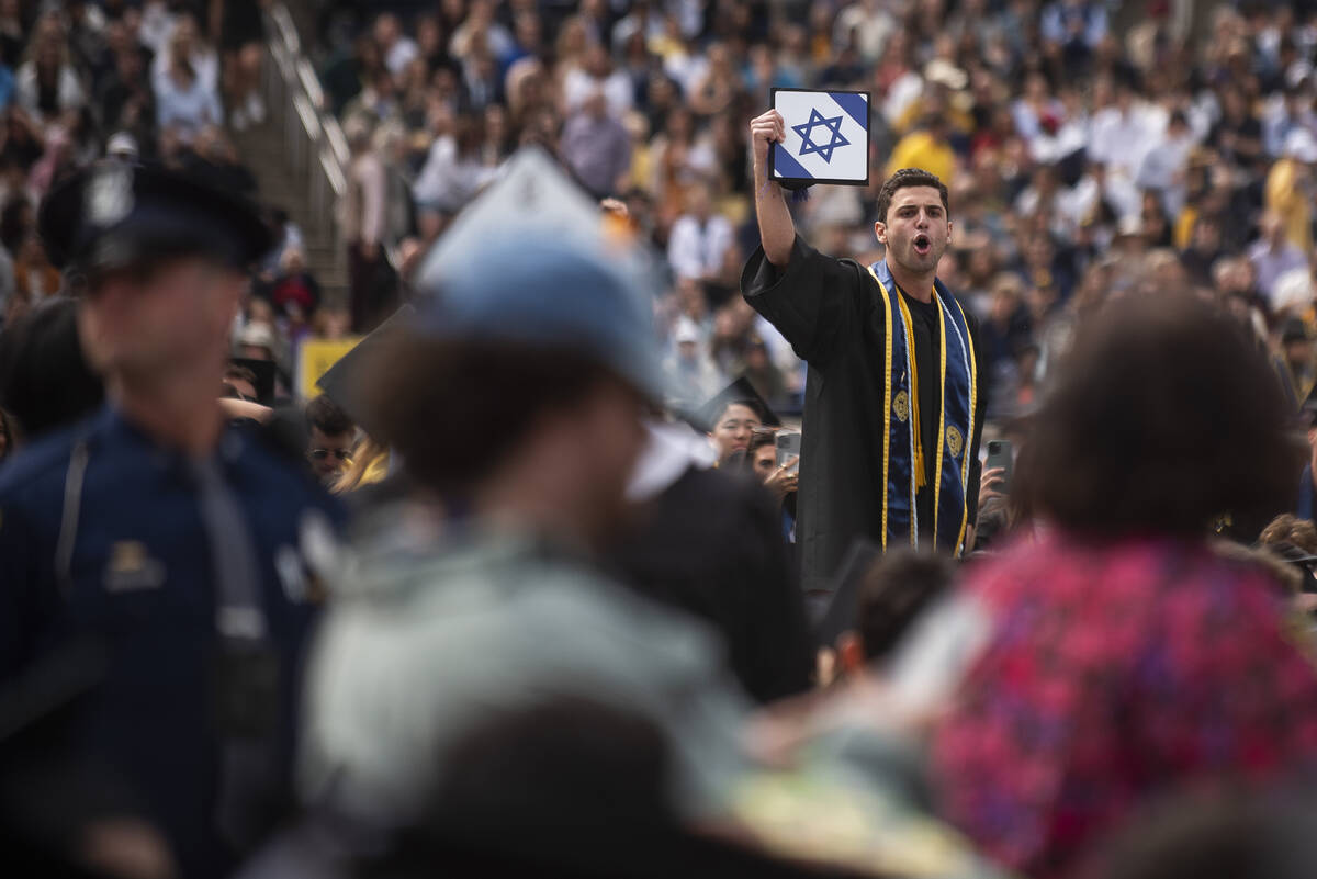 A graduate holds his cap with an Israeli flag while shouting at pro-Palestinian protesters as t ...
