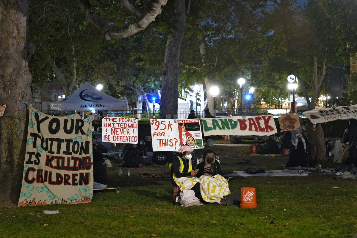People stand guard outside an encampment set up by pro-Palestinian demonstrators on the campus ...