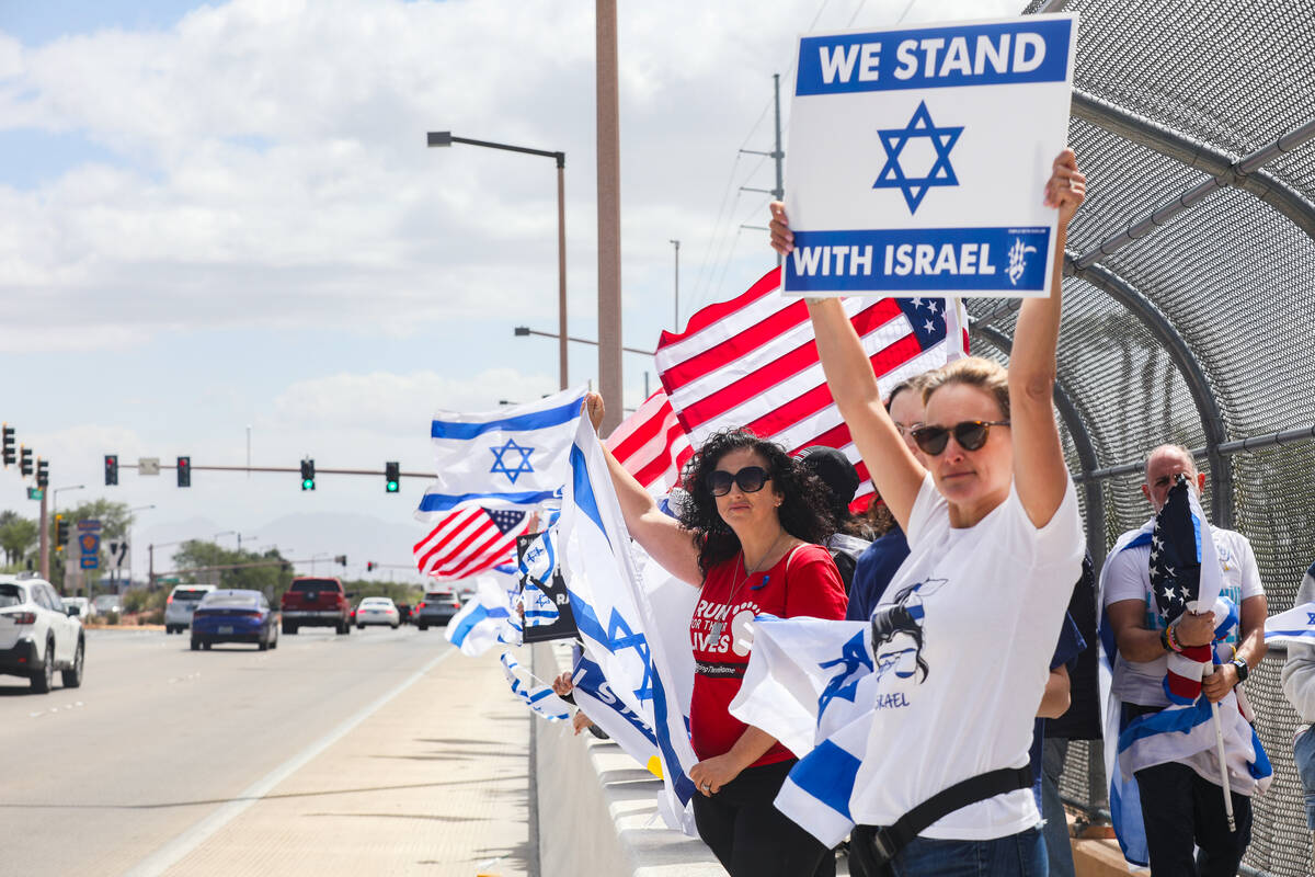 Participants wave flags and signs at passing cars on the Charleston bridge overpass on the 215 ...