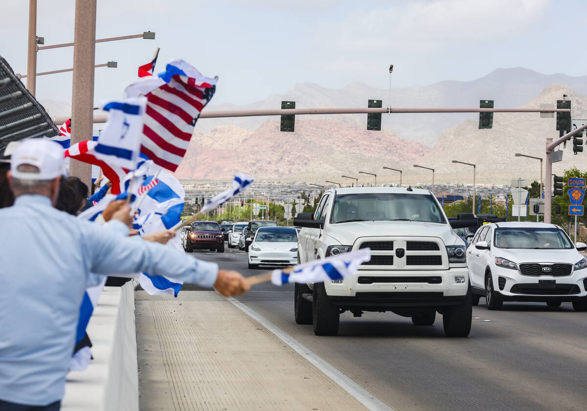 Participants wave flags and signs at passing cars on the Charleston bridge overpass on the 215 ...