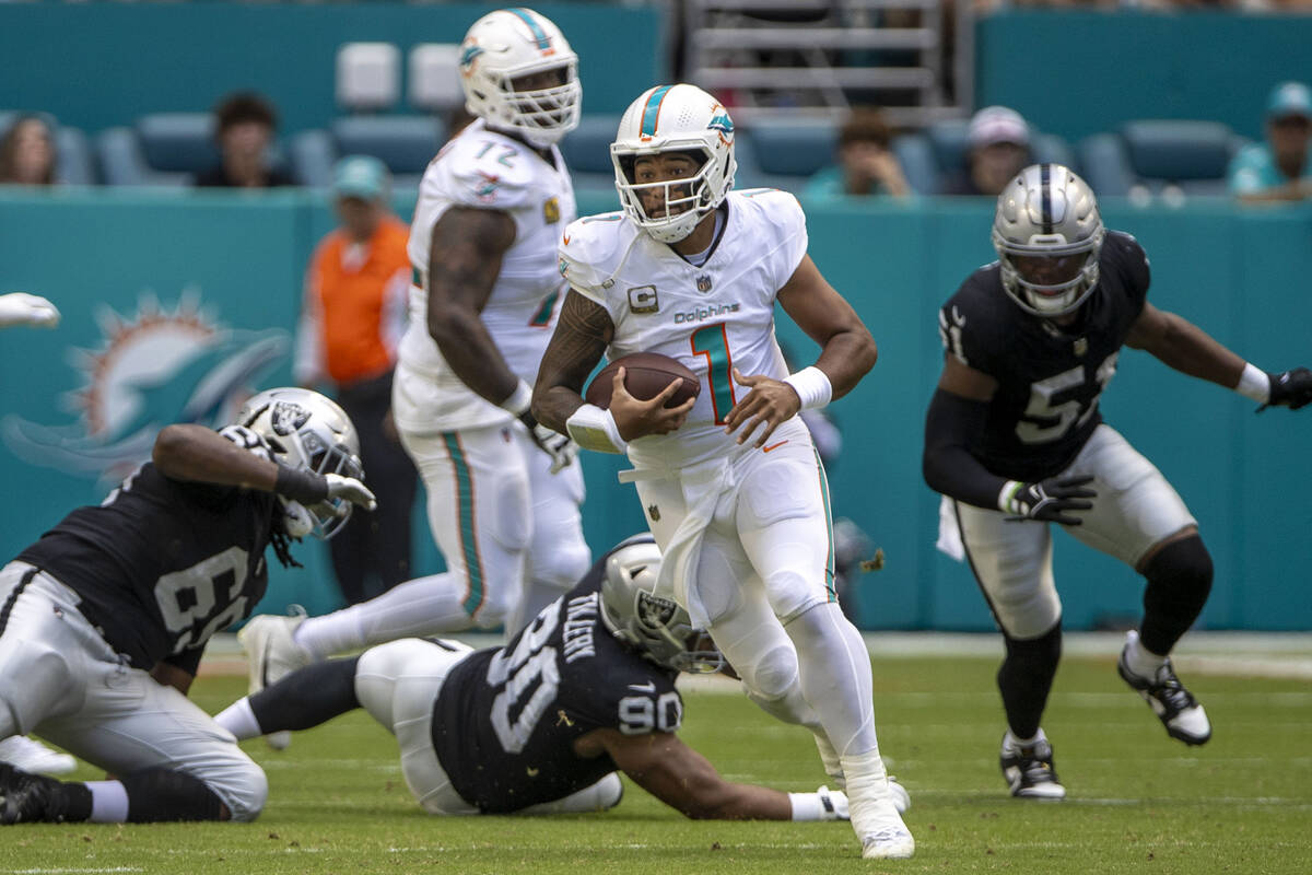 Miami Dolphins quarterback Tua Tagovailoa (1) rushes with under pressure from Raiders defensive ...