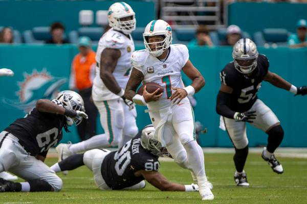 Miami Dolphins quarterback Tua Tagovailoa (1) rushes with under pressure from Raiders defensive ...