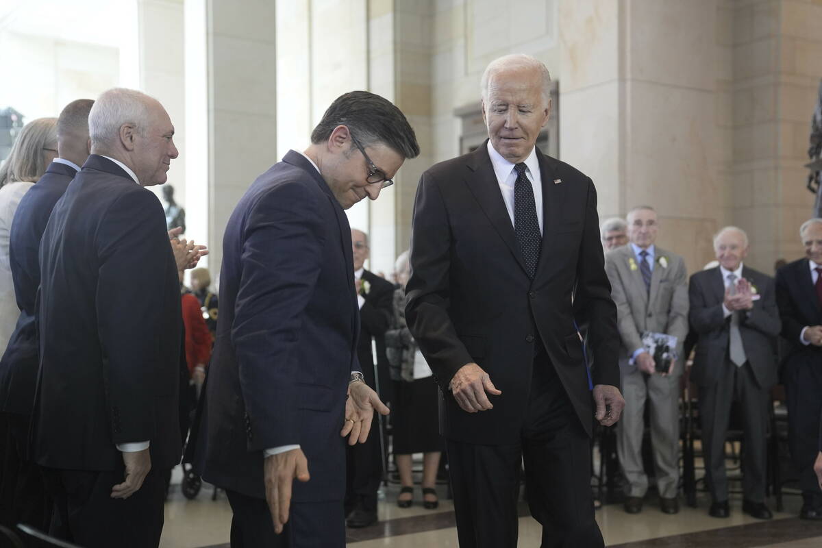 President Joe Biden walks to sit beside Speaker of the House Mike Johnson, R-La., after speakin ...