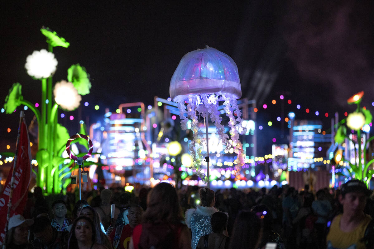 An attendee leads their group through the crowd with a jellyfish umbrella during the second day ...