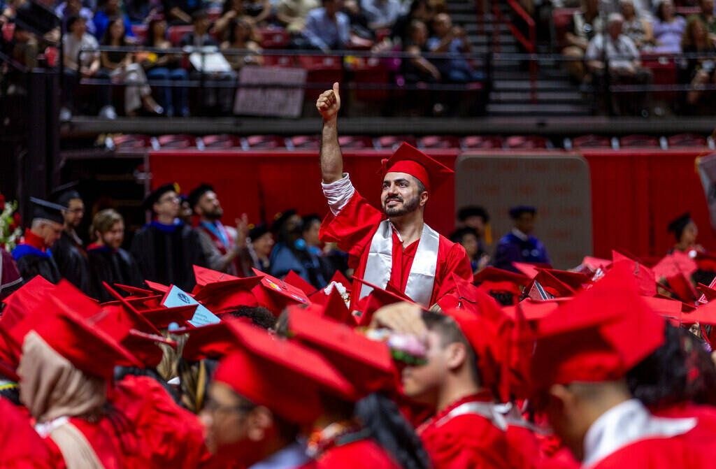 A graduate signals to those there in his support during UNLV spring graduation commencement exe ...