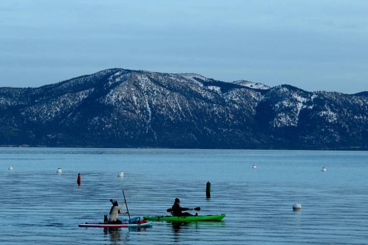 A paddle boarder and a kayaker glide across the surtface of Lake Tahoe's frigid waters on Jan. ...