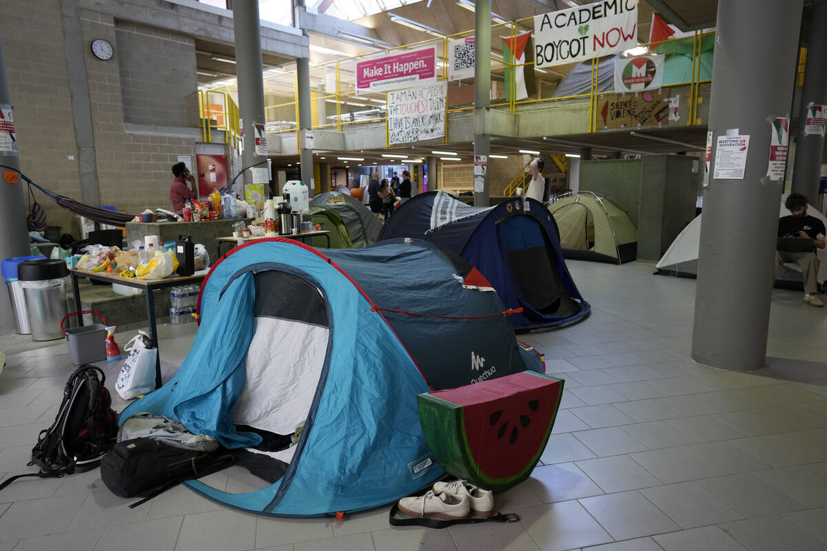 Signs and a food table are set up in a tent camp, set up by pro-Palestinian students and demons ...