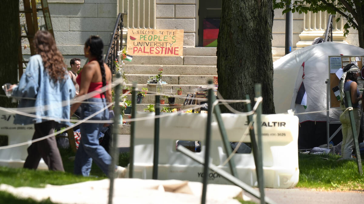 People walk past the remnants of an encampment of tents in Harvard Yard on the campus of Harvar ...