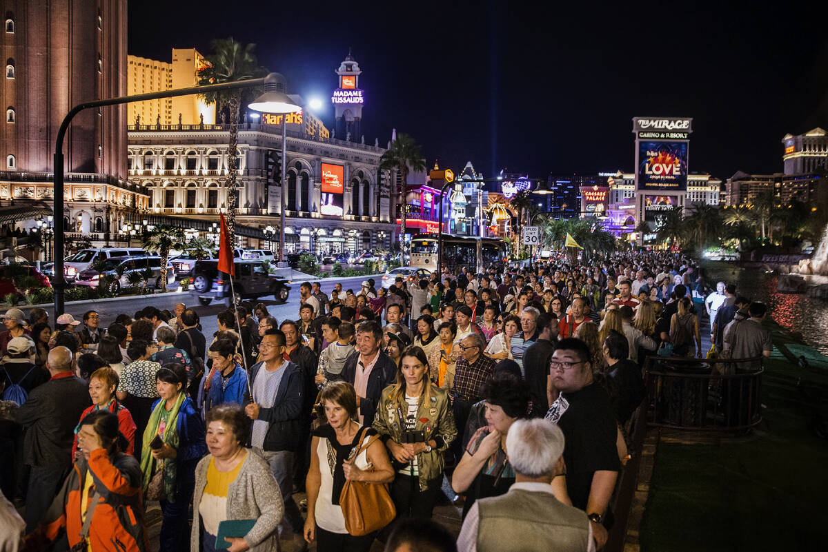 A large crowd wanders along the Las Vegas Strip as some gather to watch the volcano at The Mira ...
