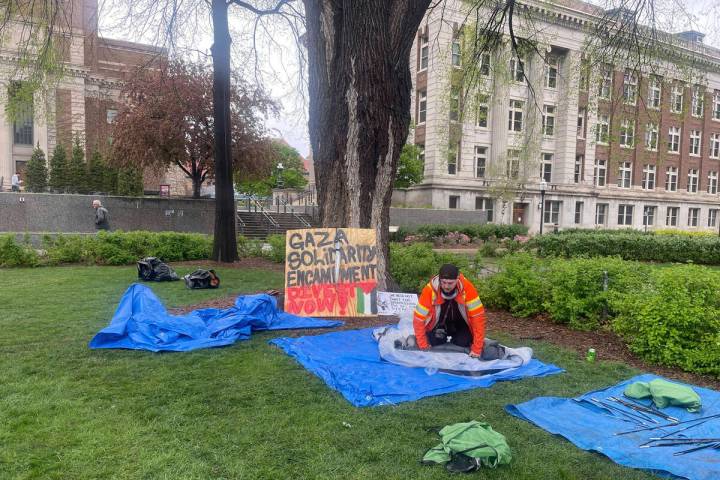 FILE - A graduate student in orange rolls up tents in front of a sign that says "Gaza Soli ...