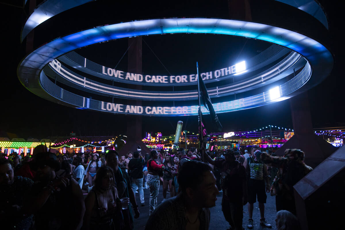 Attendees dance below an installation during the second night of the Electric Daisy Carnival at ...