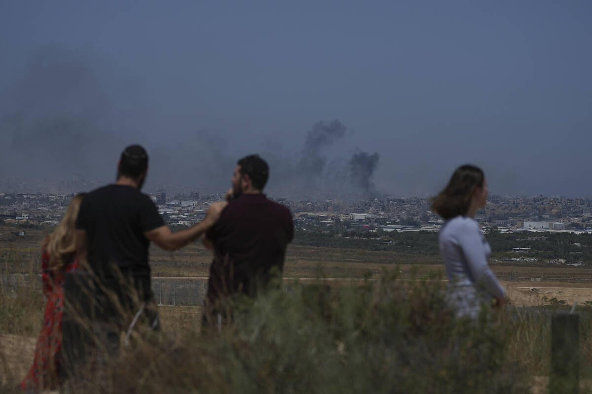People watch smoke rising to the sky after an explosion in the Gaza Strip, as seen from souther ...