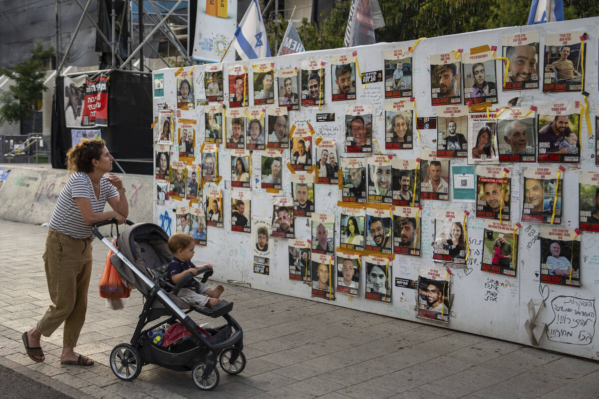 Passersby observe the photos of hostages held in the Gaza Strip that are plastered to the walls ...