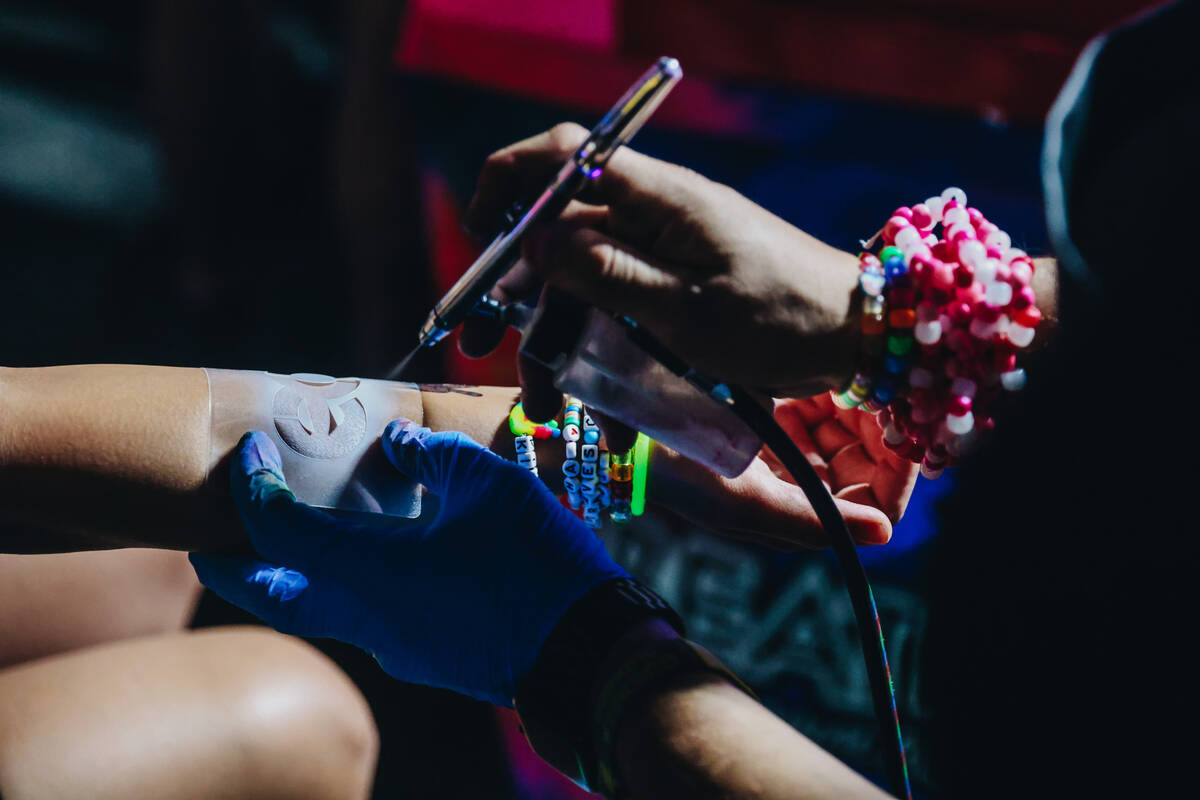 A festival attendee gets an airbrush tattoo of the EDC logo on the third and final night of the ...