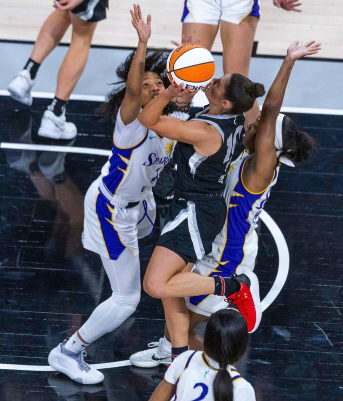 Aces guard Kelsey Plum (10) looks to gets off a shot between Los Angeles Sparks guard Zia Cooke ...