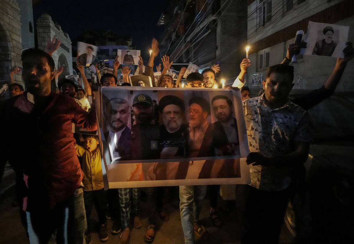 Shiite Muslims hold photos of Iranian President Ebrahim Raisi and others leaders shout slogans ...