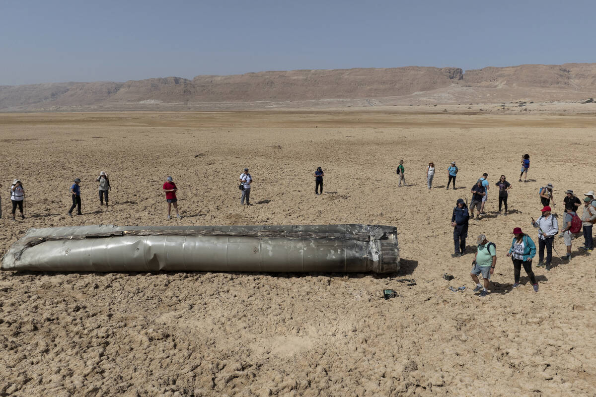 FILE - People gather around a component from an intercepted ballistic missile that fell near th ...