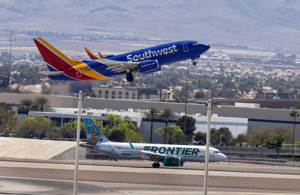 A Southwest Airlines jet takes off while a Frontier Airlines plane rolls on the tarmac at Harry ...