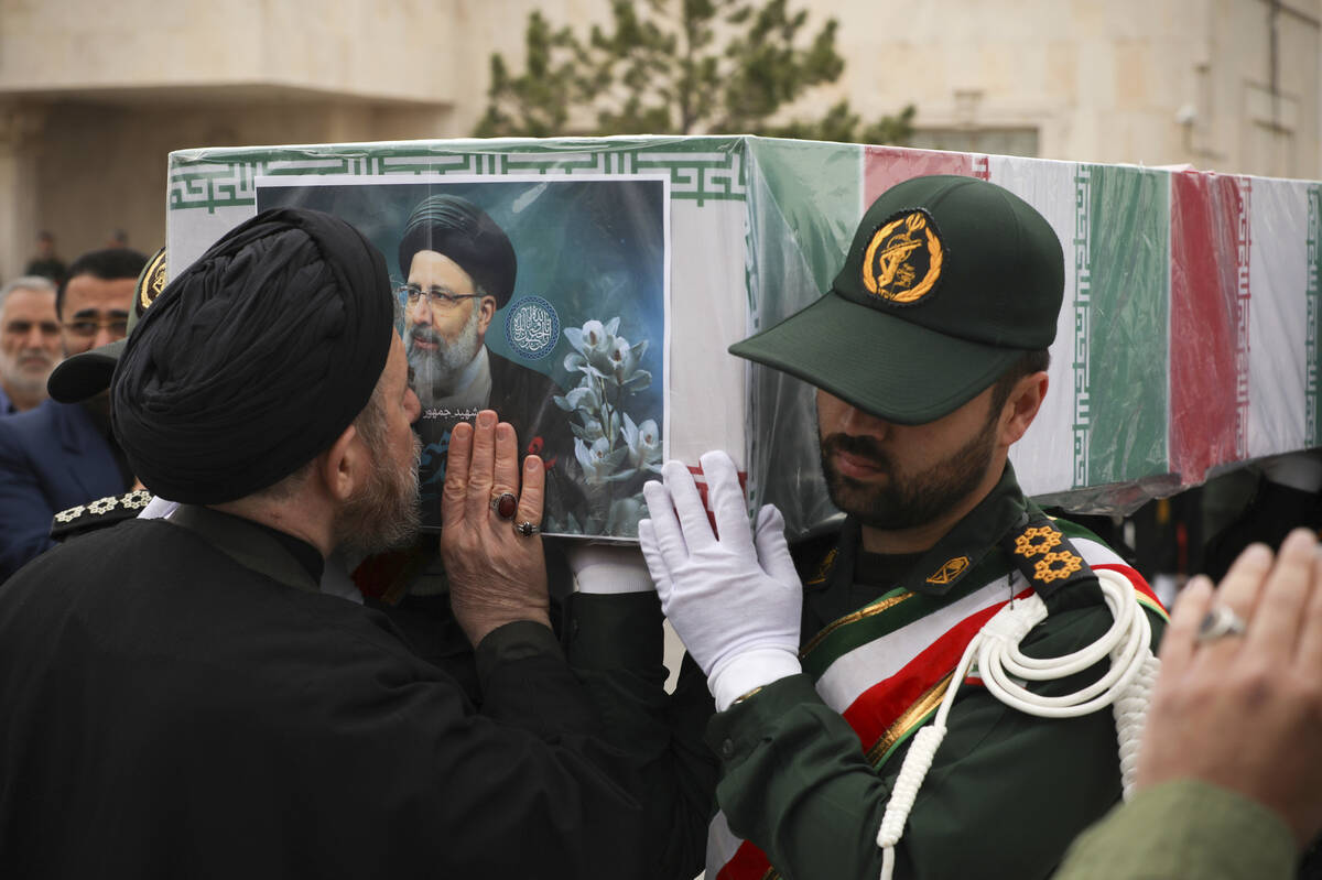 In this photo released by the Iranian Presidency Office, a cleric kisses the flag-draped coffin ...