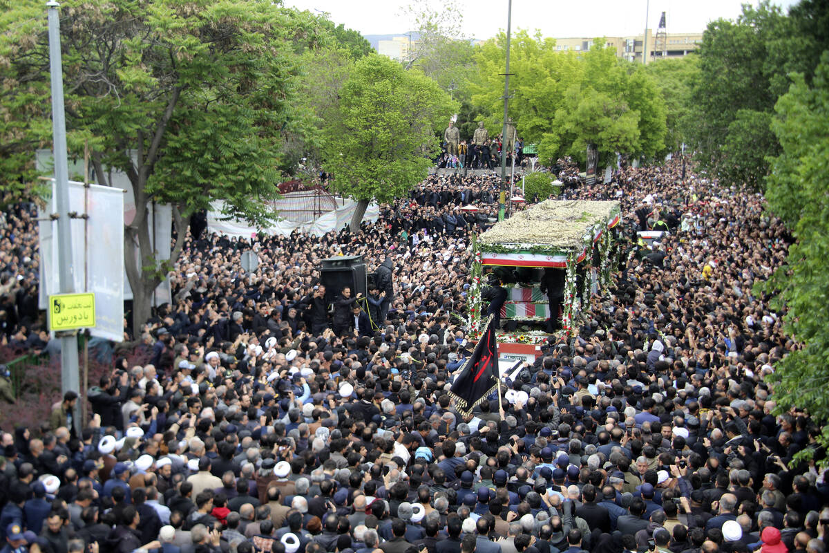 In this photo provided by Fars News Agency, mourners gather around a truck carrying coffins of ...