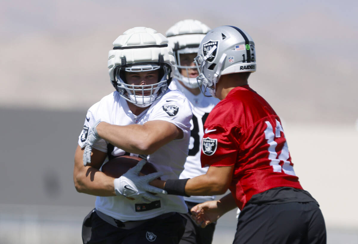 Raiders quarterback Aiden O'Connell (12) hands off to tight end Michael Mayer during organized ...