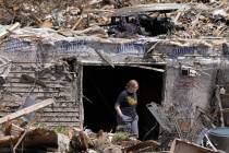 A woman walks out of the basement of a tornado damaged home, Wednesday, May 22, 2024, in Greenf ...