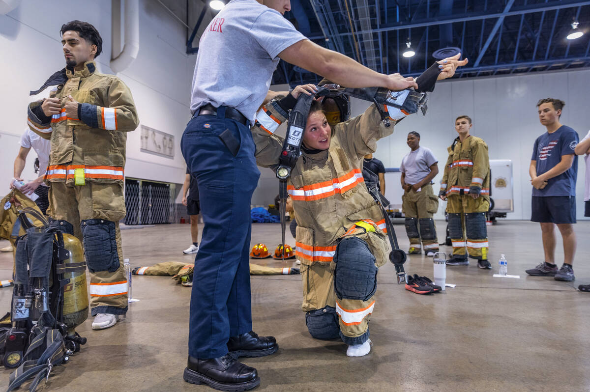 Participant Kailey Daforno, 15, is assisted by an explorer while putting on an oxygen tank duri ...