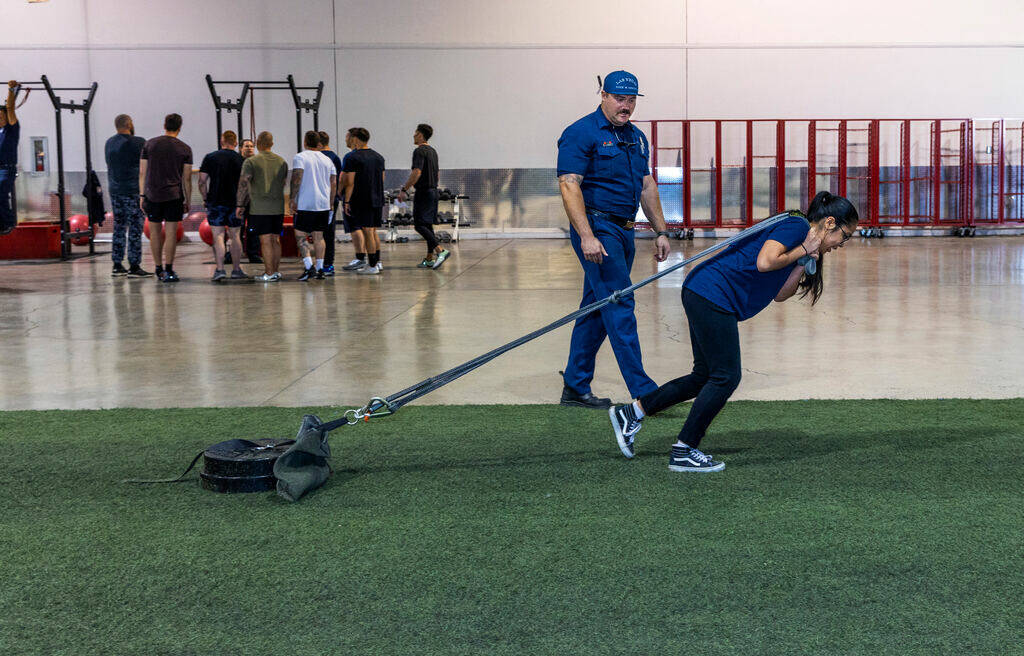 Participant Nathalie Cotton is encouraged by firefighter Tony Brown as she drags a weighted sle ...