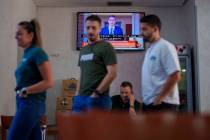 Customers stand in a restaurant while Spanish Prime Minister Pedro Sanchez appears on a televis ...