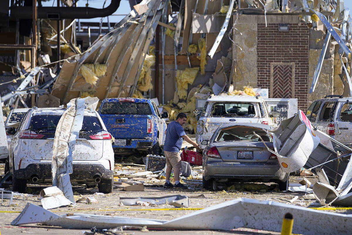A man looks at a damaged car after a tornado hit the day before, Sunday, May 26, 2024, in Valle ...
