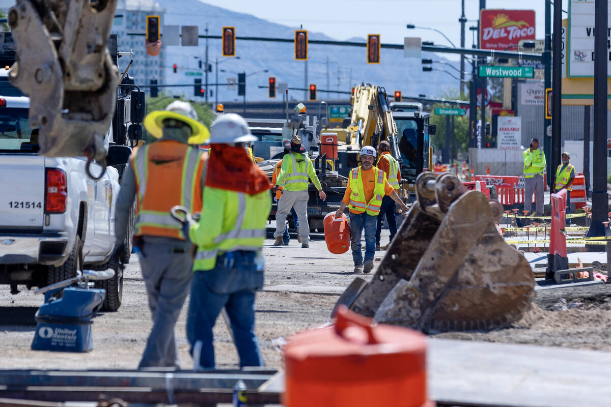 A construction worker carries a water cooler on a road project along West Charleston Boulevard ...