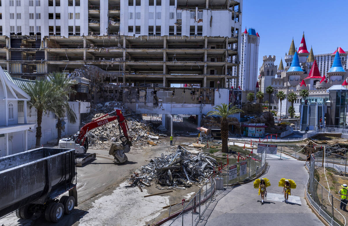 Showgirls carry hydration as they pass by the Tropicana demolition as workers there use protect ...