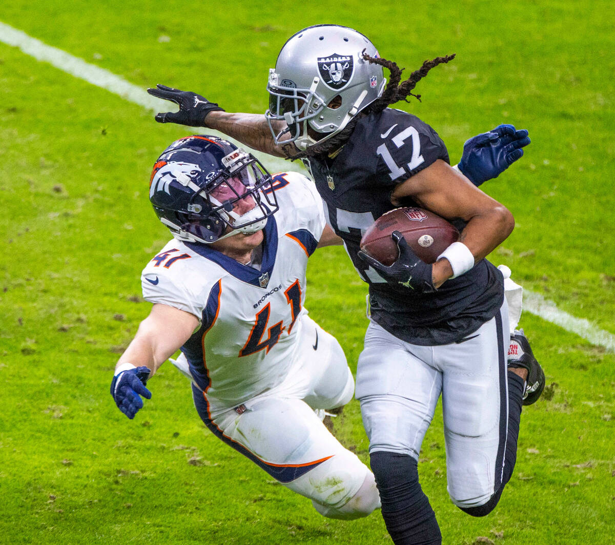 Raiders wide receiver Davante Adams (17) stiff arms Denver Broncos linebacker Drew Sanders (41) ...