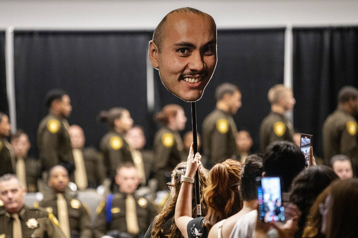 Friends and families cheer and take photographs of graduates as they receive their badges and d ...