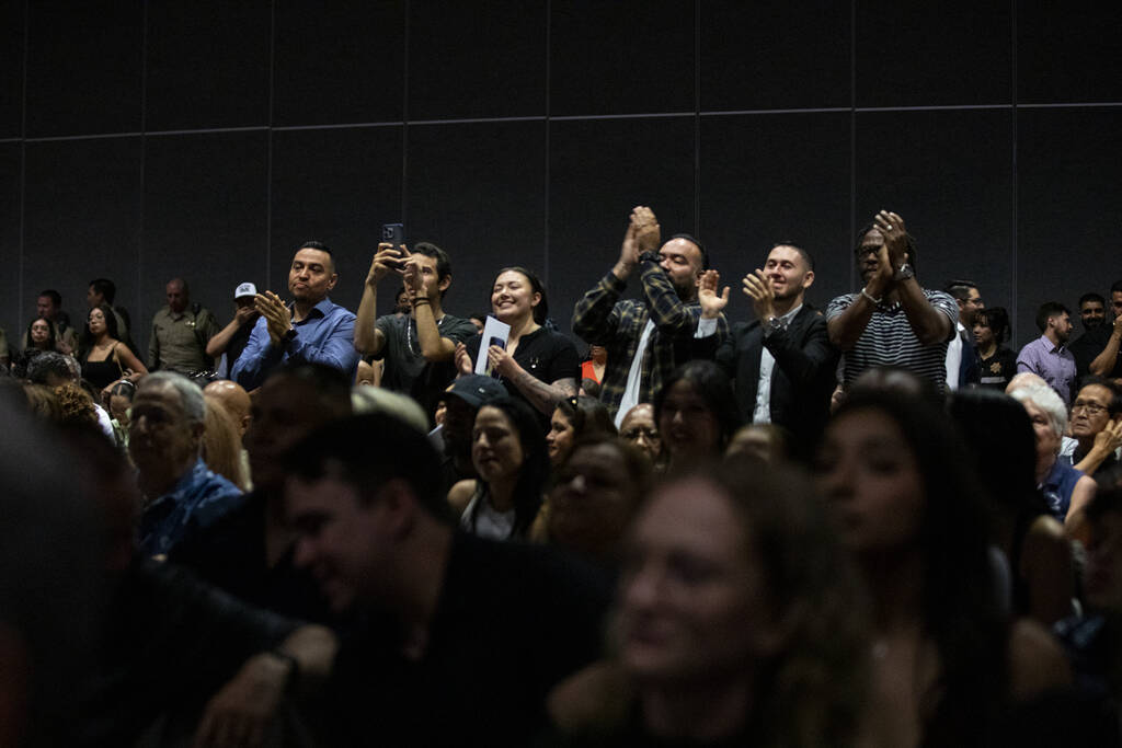 Friends and families cheer and wait to take photographs of graduates as they receive their badg ...