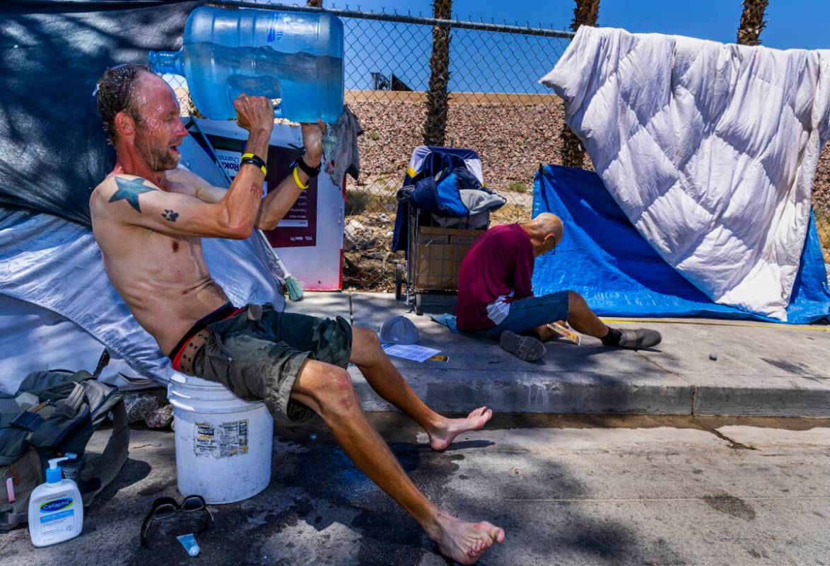 Homeless man Milton John Scott III pours a jug of water on his head to escape the heat and wash ...