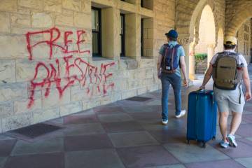 Students walk by graffiti near university president Richard Saller's office at Stanford Univers ...