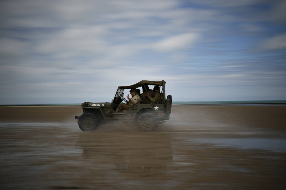 Reenactors drive a vintage US Army jeep along Utah Beach near Sainte-Marie-du-Mont, Normandy, F ...
