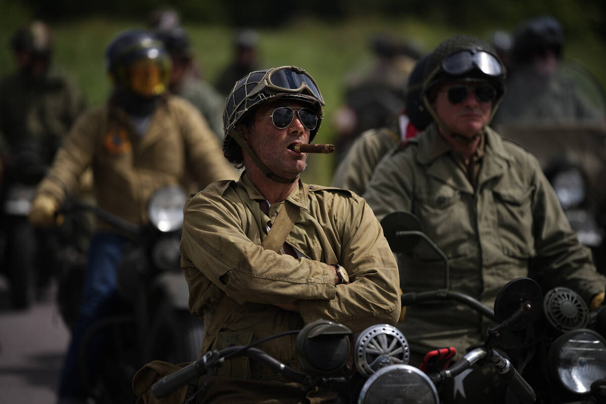 A reenactor smokes a cigar while riding a US army vintage Harley Davidson motorbike at Utah Bea ...