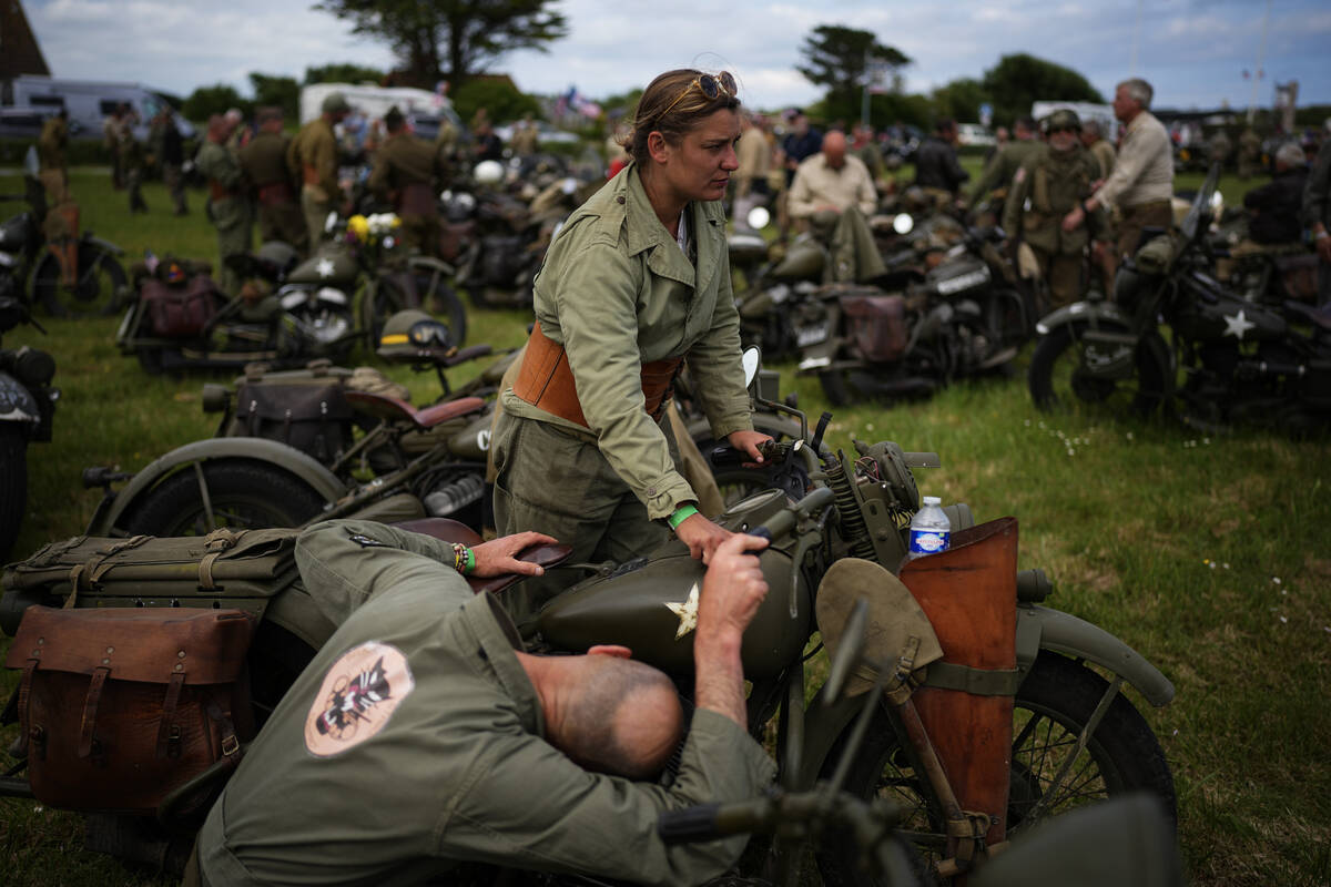 Reenactors riding US army vintage Harley Davidson motorbikes stop for a rest at Utah Beach near ...