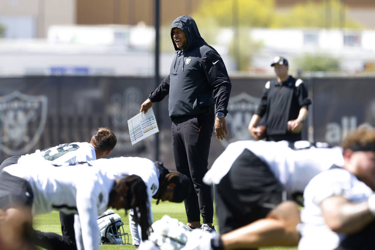 Raiders head coach Antonio Pierce watches his players stretch during team's practice at the Int ...