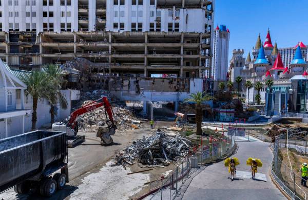 Showgirls carry hydration as they pass by the Tropicana demolition as workers there use protect ...