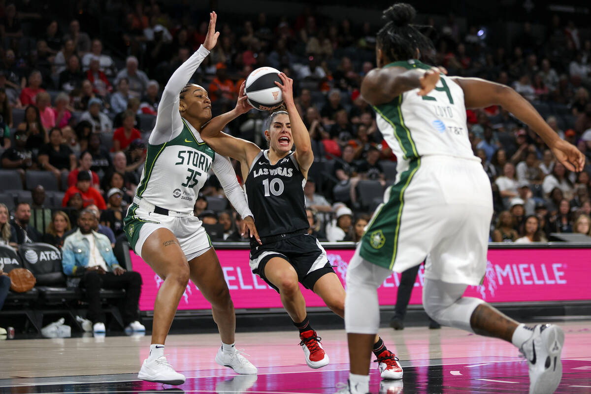 Las Vegas Aces guard Kelsey Plum (10) drives toward the hoop between Seattle Storm guard Victor ...