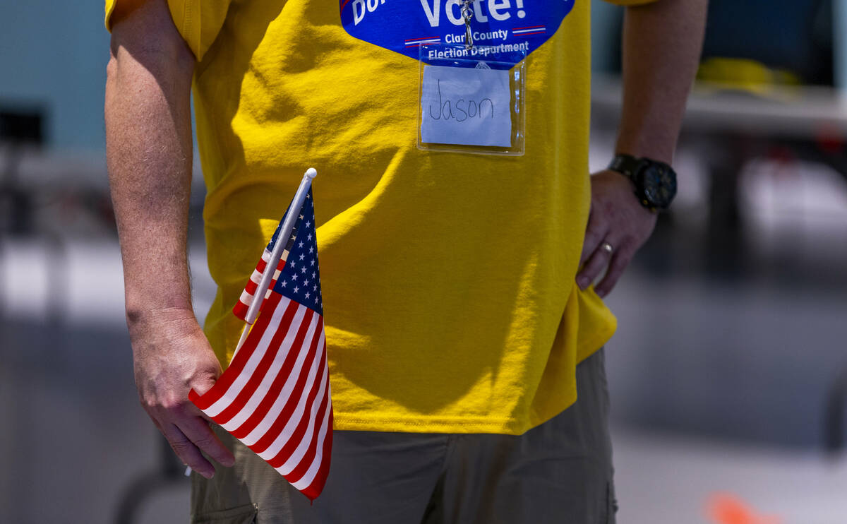 A poll worker carries a small flag to direct voters on Nevada's primary election day at the Sum ...