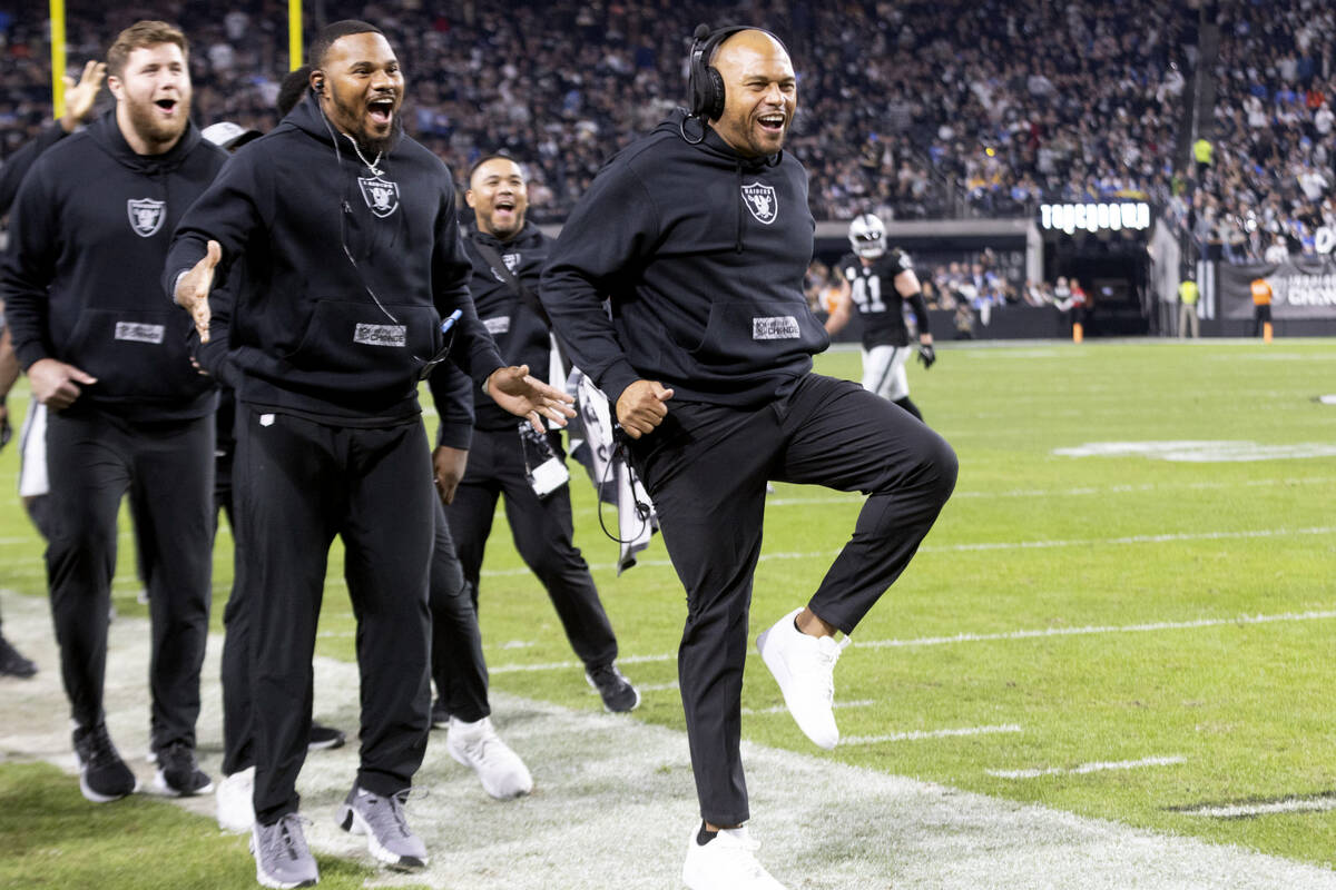 Raiders head coach Antonio Pierce, right, high-steps to celebrate as defensive tackle John Jenk ...