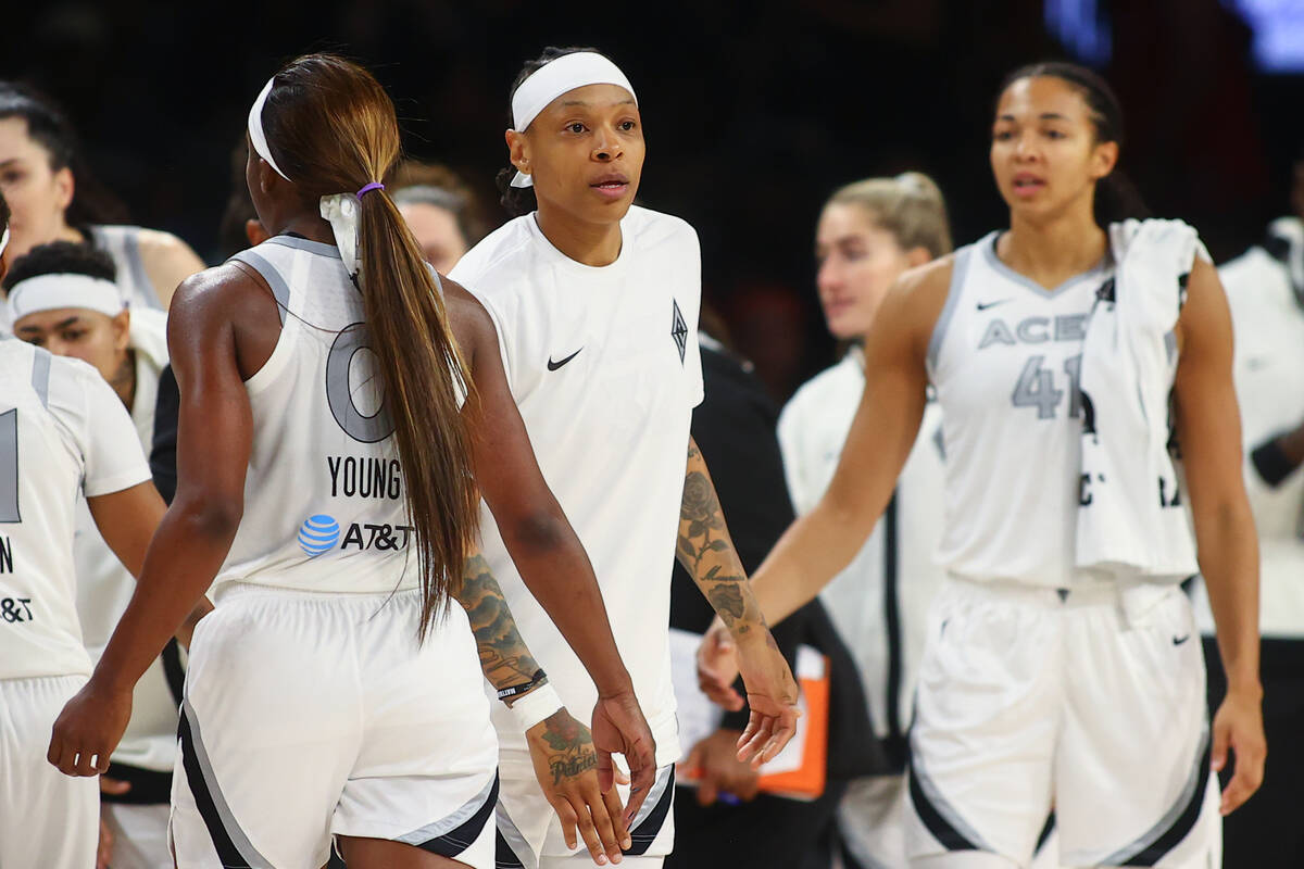 Las Vegas Aces forward Emma Cannon, center, high fives guard Jackie Young (0) before a timeout ...