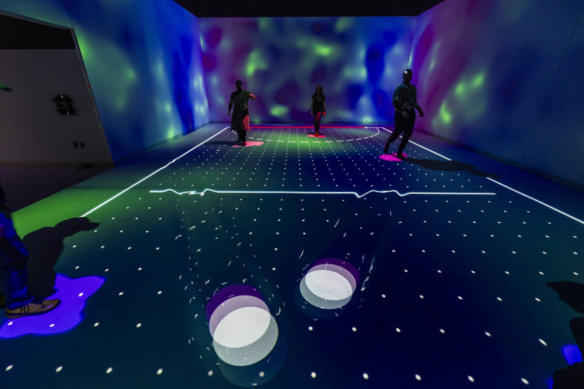 People play light hockey by kicking light projections with their feet at Electric Playhouse, a ...